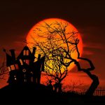 Spooky Halloween House on hill with tree against harvest moon.